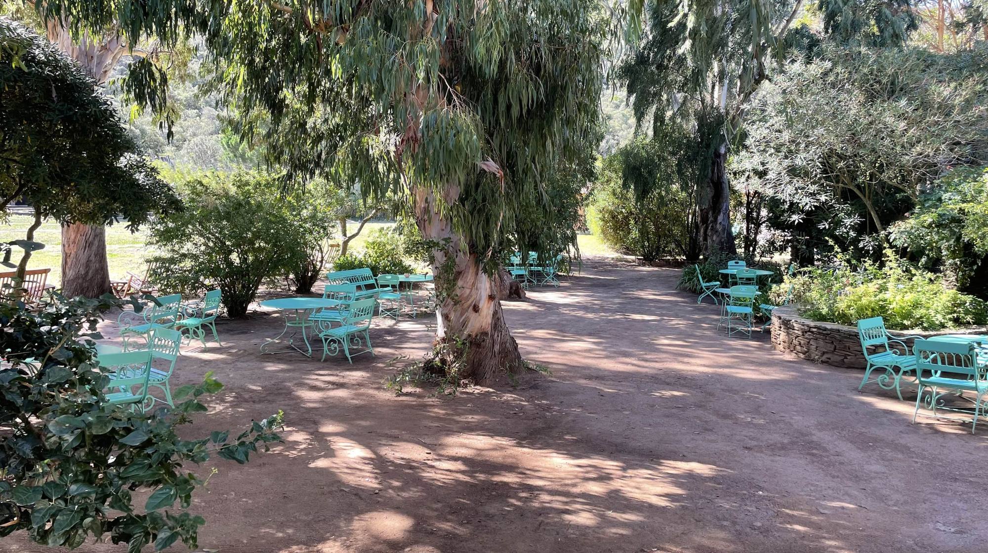 Petit jardin ombragé du Manoir avec mobilier vert d'eau sous les eucalyptus